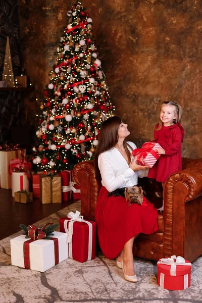 cute girl and mom at home near the christmas tree with gifts.