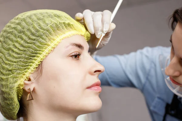 woman on the procedure of lamination and coloring of eyebrows at the beautician in the salon