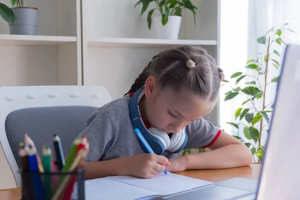 티셔츠를 소녀는 헤드폰을 집에서 컴퓨터로 공부하고 공부하고 숙제를 인터넷으로 의사소통을 — 스톡 사진