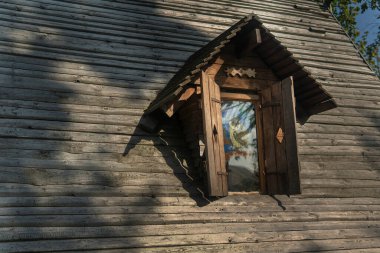 Eski bir evin ahşap çatısında klasik kepenkli bir pencere..