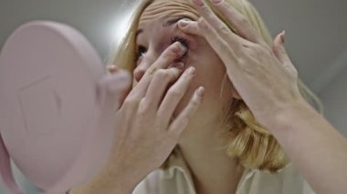 blonde teen girl removes contact lenses from her eyes
