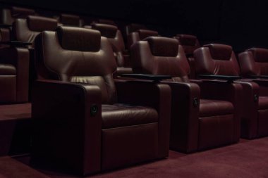 Coronavirus karantinası sırasında boş bir sinema salonundaki kahverengi deri koltuklar..