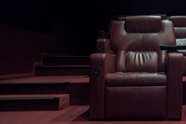 Coronavirus karantinası sırasında boş bir sinema salonundaki kahverengi deri koltuklar..