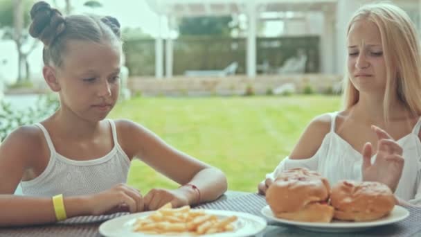 Twee tieners vriendinnen duwen borden fastfood weg en willen het niet eten. — Stockvideo