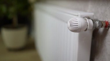 a woman's hand opens the valve on the radiator of the heating battery to warm the apartment from the cold in winter.