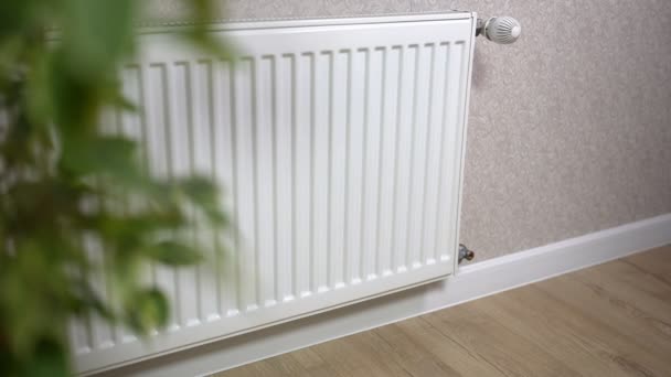 La fille se lève et touche le radiateur froid de la batterie et ouvre la vanne pour échapper au froid à la maison — Video