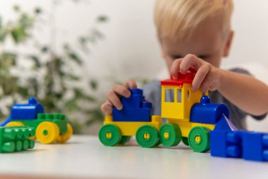 Bir çocuk dikkatlice bir çocuk treni inşa eder..