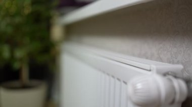 Kadın elleri akünün soğuk radyatörüne dokunur ve evdeki soğuktan kaçmak için vanayı açar..