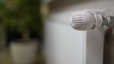 Kadın elleri akünün soğuk radyatörüne dokunur ve evdeki soğuktan kaçmak için vanayı açar..