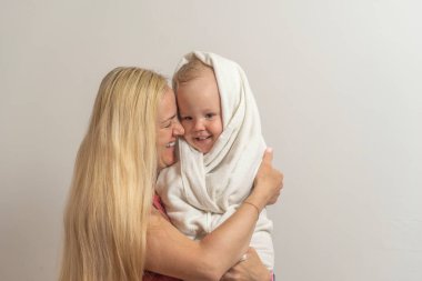 Anne, arka planda banyo yaptıktan sonra oğlunu kucağına aldı..