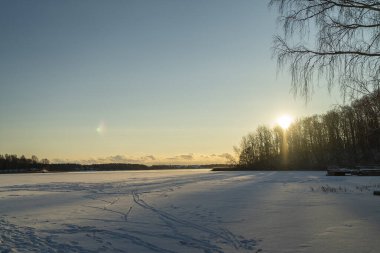 Kış manzarası batan güneşte buzla kaplı göl.