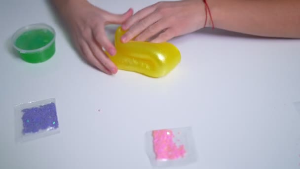 Girls hand playing with yellow shiny slime at the table at home — Stockvideo