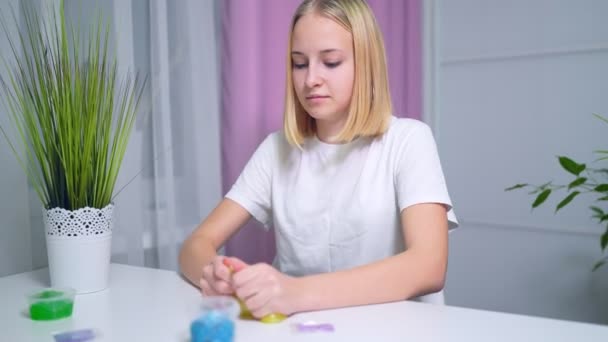 Girl playing with yellow shiny slime at the table at home — Stockvideo