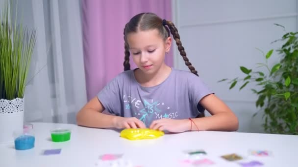 Teen girl playing with green shiny slime at the table at home — Stockvideo