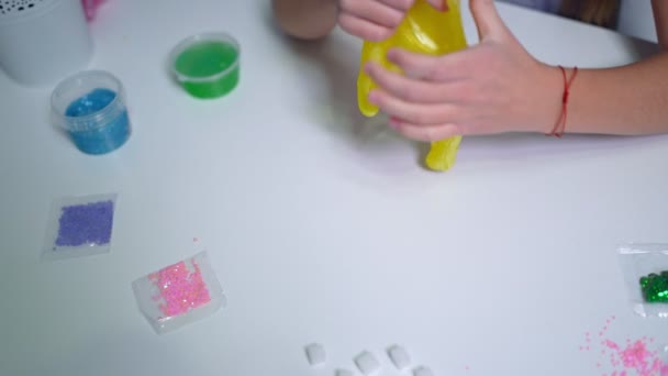 Meisjes Hand Spelen Met Geel Glanzend Slijm Aan Tafel Thuis — Stockvideo