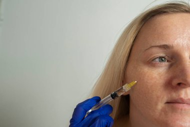 Genç bir kadın kozmetik cilt enjeksiyonu, yüz mezoterapisi ve kozmetik bakım yapar.