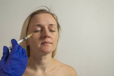 Genç bir kadın kozmetik cilt enjeksiyonu, yüz mezoterapisi ve kozmetik bakım yapar.