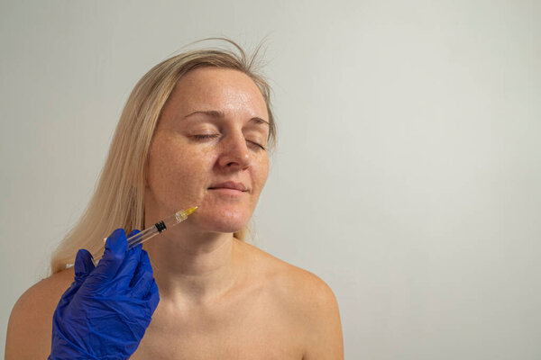 молодая женщина делает косметические инъекции кожи, лицевую мезотерапию с косметическим уходом