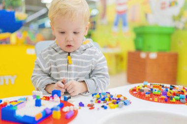 Küçük çocuk masada renkli küp bulmacaları oynuyor..