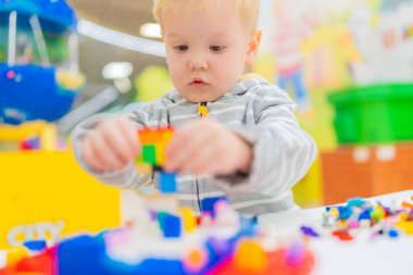 Küçük çocuk masada renkli küp bulmacaları oynuyor..