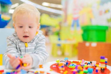 Küçük çocuk masada renkli küp bulmacaları oynuyor..