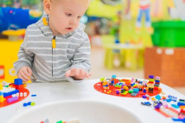 Küçük çocuk masada renkli küp bulmacaları oynuyor..