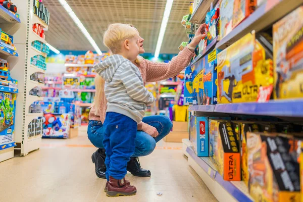 Mom chooses a gift from a toy store for her son.