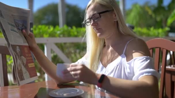 Blondynka Okularach Czyta Gazetę Pije Kawę Miejskiej Kawiarni — Wideo stockowe