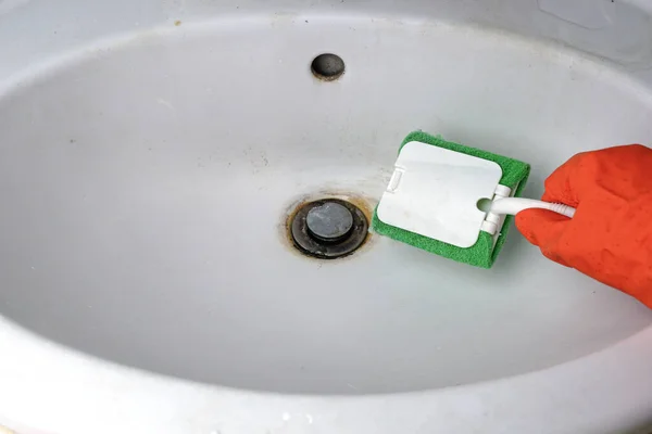 Person hand holding a sponge and cleans a dirty sink in rust, Clean dirty sinks. Homework concept.
