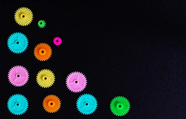 Colorful gears on a black background, concept of work process movement gears