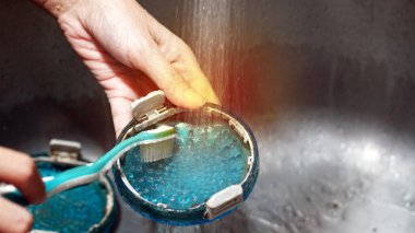 Çamaşır makinesindeki enkaz filtresi fırçayla temizleniyor.