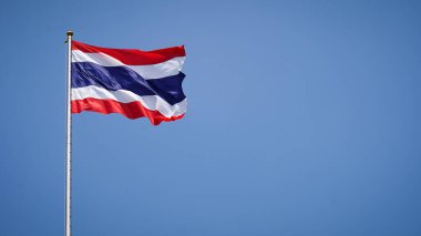 Tayland 'ın ulusal bayrağı mavi arka planda dalgalanıyor. Yan tarafta boş alan var.