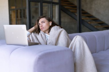 Kışın kanepede, rahat bir battaniyenin altında, dizüstü bilgisayarda televizyon seyreden, zaman öldüren sıkıcı bir kadın.