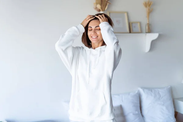 Młoda Kobieta Domu Sypialni Ciepłej Białej Bluzie Kapturem Szczęśliwa Pozująca — Zdjęcie stockowe