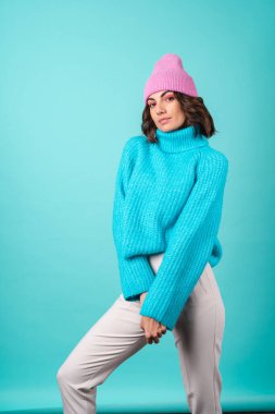 Mavi kazaklı ve parlak makyajlı pembe şapkalı genç bir kadının samimi portresi.