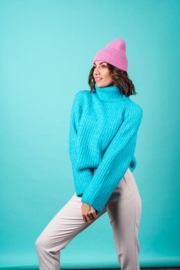 Mavi kazaklı ve parlak makyajlı pembe şapkalı genç bir kadının samimi portresi.