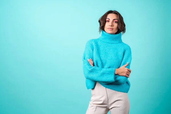 ニットの青いセーターと明るいピンクのメイクでターコイズの背景に若い女性の居心地の良い肖像画 — ストック写真