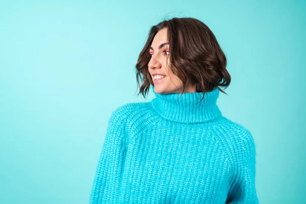ニットの青いセーターと明るいピンクのメイクでターコイズの背景に若い女性の居心地の良い肖像画 — ストック写真