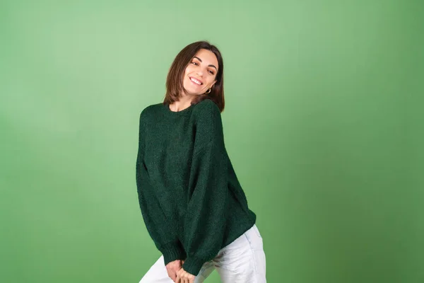 若いです女性上の緑の背景でA居心地の良い大きなニットセーターかわいいです笑顔 — ストック写真
