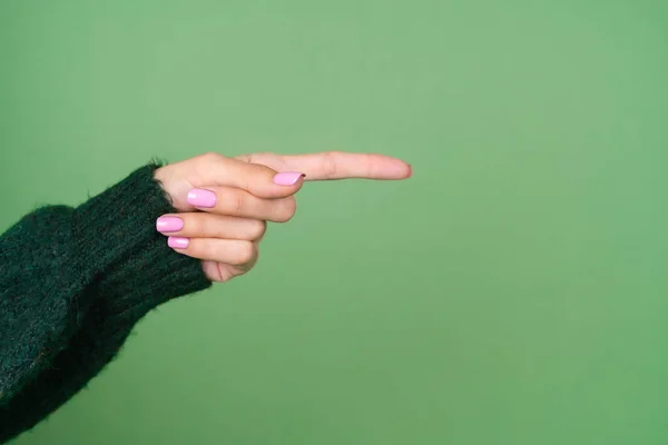 Mano Mujer Sobre Fondo Verde Suéter Apunta Hacia Lado —  Fotos de Stock