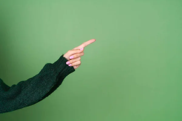 Frauenhand Auf Grünem Hintergrund Pullover Zeigt Zur Seite — Stockfoto
