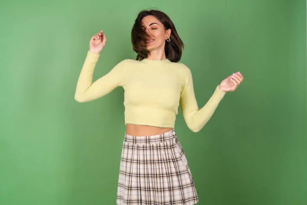 Young Woman Green Background Yellow Sweater Plaid Skirt Smiles Cutely — Stock Photo, Image