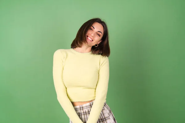 Νεαρή Γυναίκα Πράσινο Φόντο Κίτρινη Μπλούζα Και Καρό Φούστα Χαμογελάει — Φωτογραφία Αρχείου