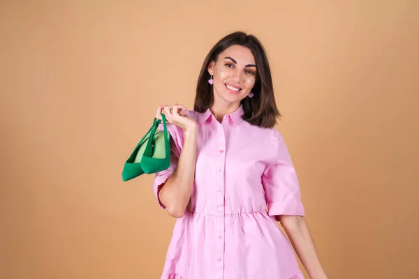 一个穿着米色背景的粉色连衣裙的年轻女子的画像 脸上闪烁着灿烂的妆容 带着浪漫的绿色抽水机 — 图库照片