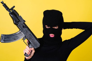 Genç, seksi, pembe dudaklı, kar maskeli, elinde makineli tüfek, haydut, hırsız, kanun kaçağı bir kadın.