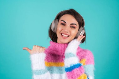 Mavi arka planda parlak renkli bir süveter giyen genç bir kadın. Kulaklıkları çıkartıyor, en sevdiği müziğin keyfini çıkarıyor. Parmağını sola çeviriyor.