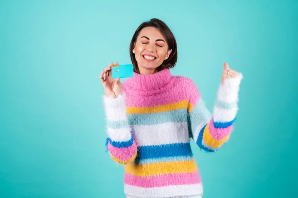 파란색 배경에 색상의 스웨터를 여자가 카드를 행복하게 점프하고 있습니다 — 스톡 사진