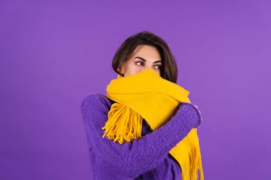 Young woman in purple soft cozy sweater and yellow scarf with makeup posing in studio
