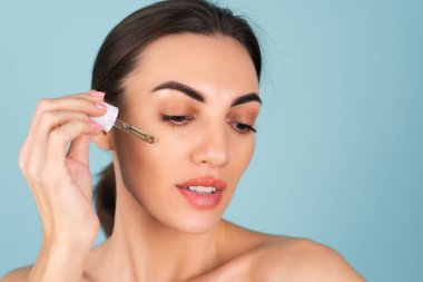Mükemmel ciltli ve doğal makyajlı üstsüz kadının yakın güzellik portresi, gençlik ve cilt suyu için serum, kozmetik yağlı damlatıcı.