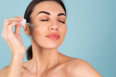 Mükemmel ciltli ve doğal makyajlı üstsüz kadının yakın güzellik portresi, gençlik ve cilt suyu için serum, kozmetik yağlı damlatıcı.